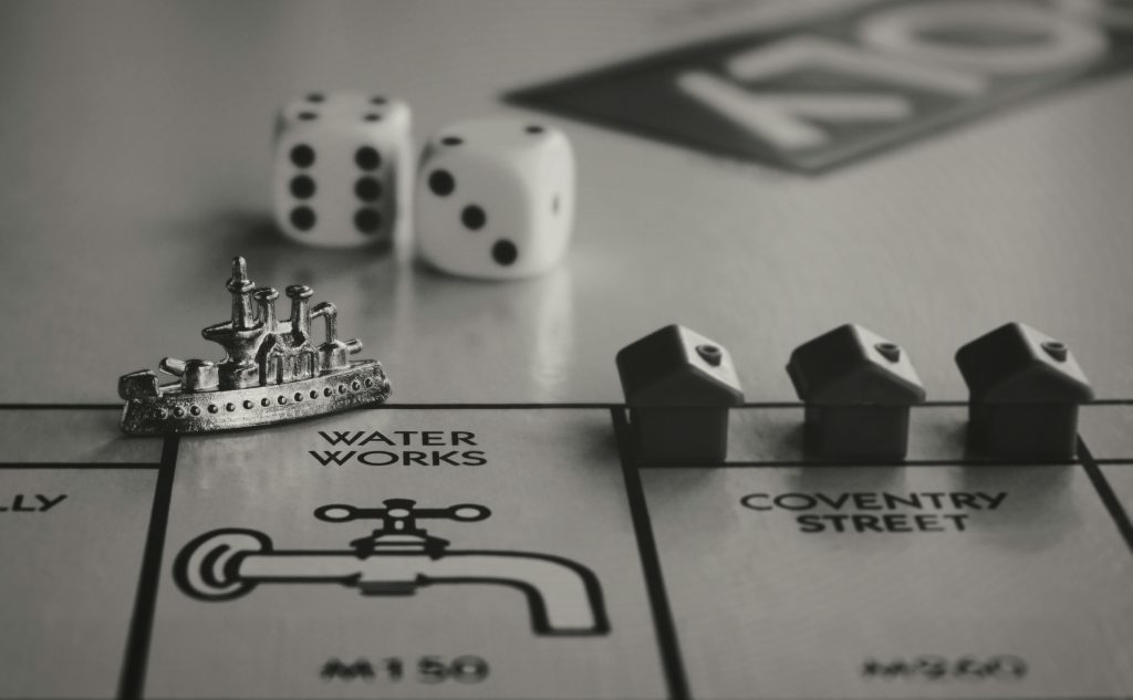 Detailed monochrome close-up of Monopoly game board with ship token, dice, and houses.